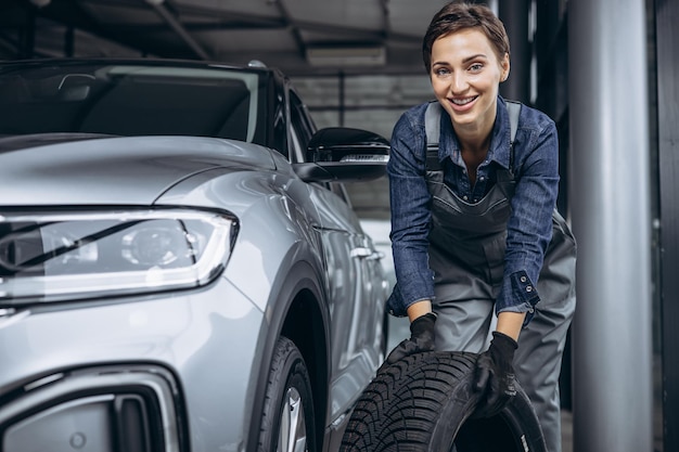 Woman car mechanic changing tires at car service
