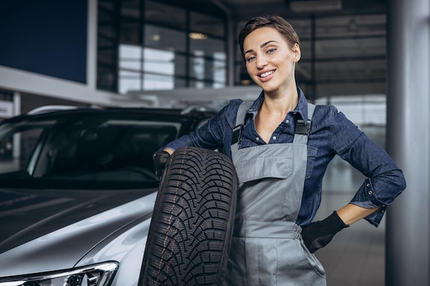 Woman car mechanic changing tires at car service