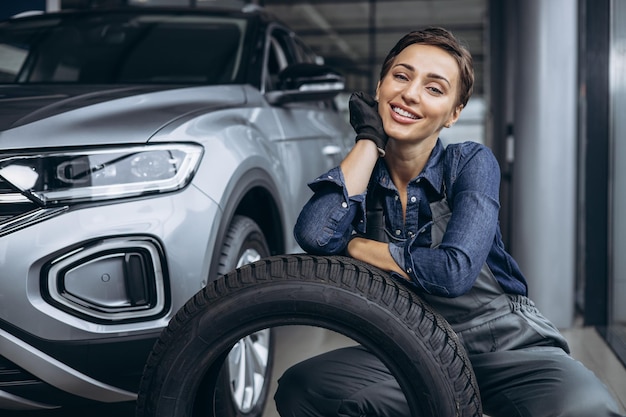 Woman car mechanic changing tires at car service