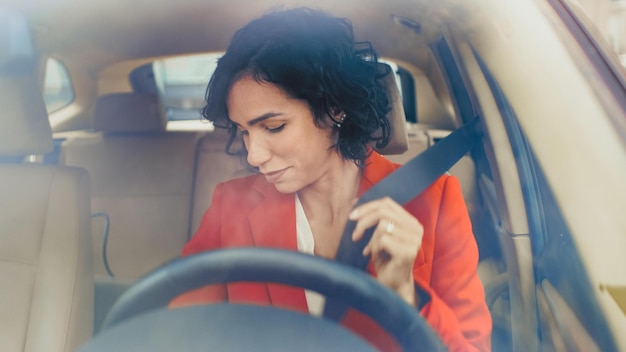 A woman in a car with a seatbelt on her head