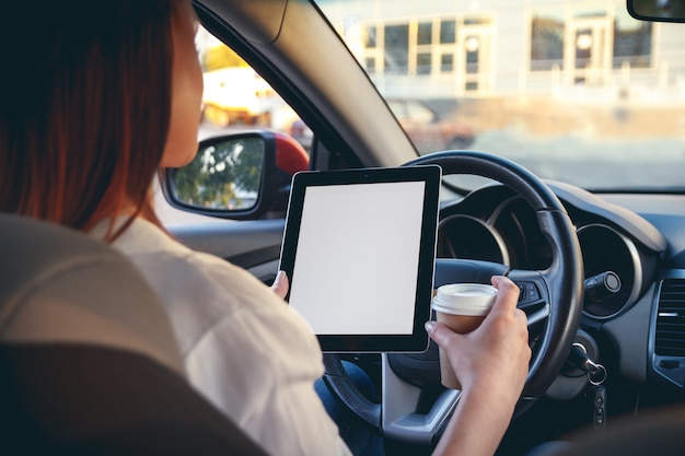 Woman in a car with a tablet in hands