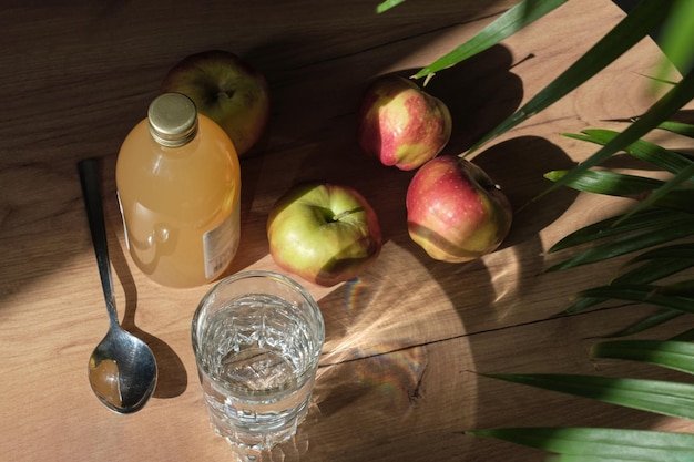 Photo woman carefully pours apple cider vinegar into a spoon adding it to a glass of water to create a