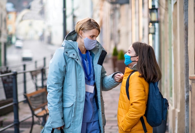 Woman caregiver nurse or healthcare worker outdoors on the way to work with schoolgirl daughter