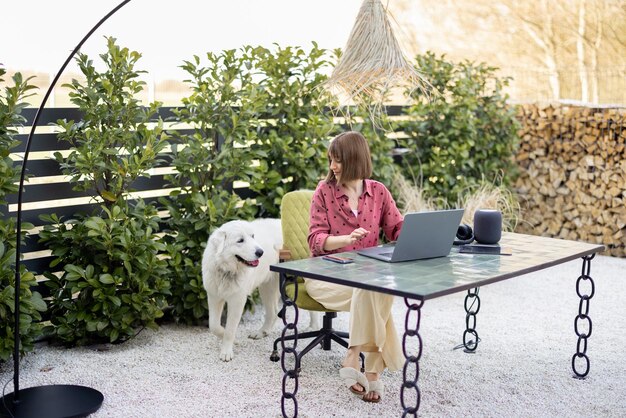 Woman cares her dog while working at outdoor office in cozy garden