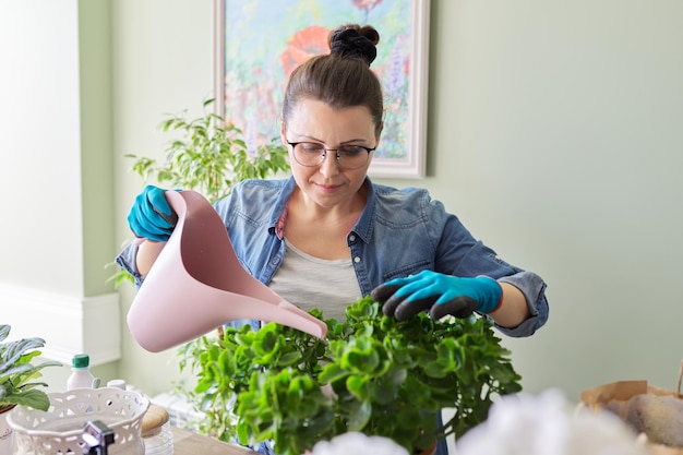 家の中で屋内植物の趣味や余暇の自然を世話する女性