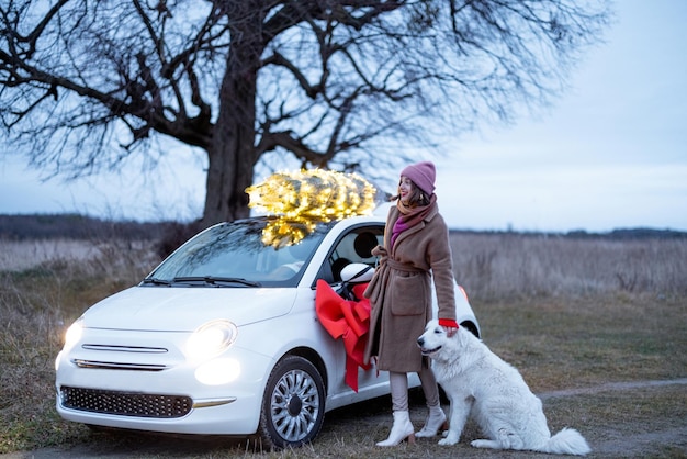 Woman carries Christmas tree by car