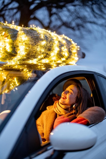 Woman carries Christmas tree by car