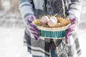 Photo woman carries an easter nest in the snow
