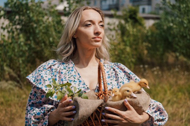 Woman carries small yellow ducklings in a basket