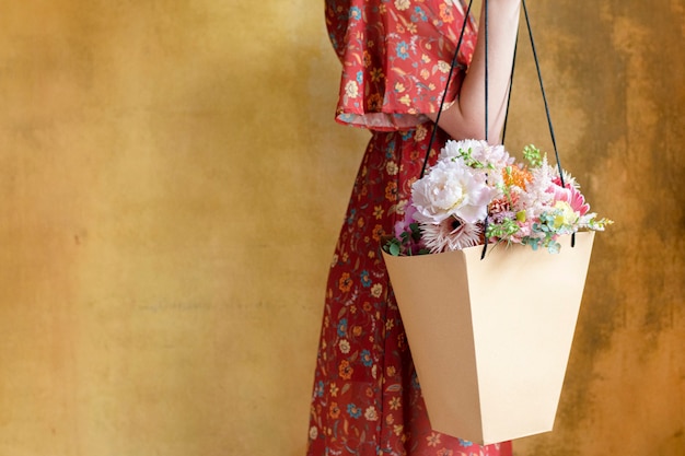 Женщина, несущая букет цветов в бумажном пакете