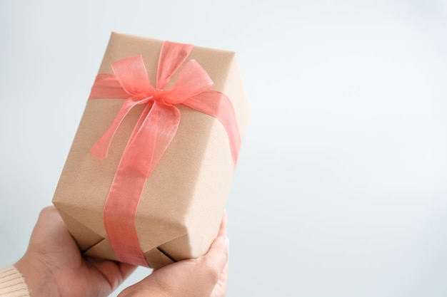Женщина с подарочной бумажной коробкой завязывает милую ленту для особого случая
