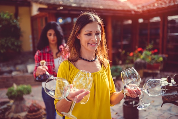 Woman carrying wine glasses at backyard patio