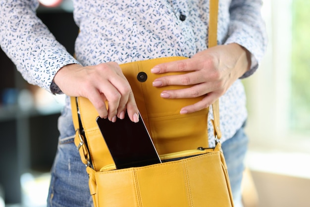 Woman in casual clothes hides smartphone in yellow bag