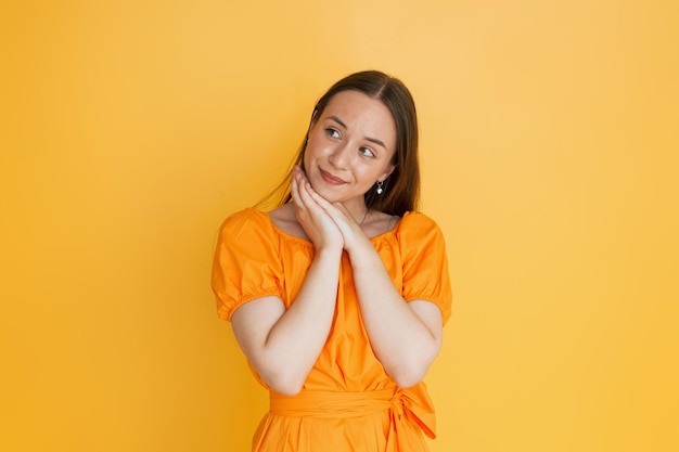 Woman in casual clothes is dreaming when standing indoors in the studio