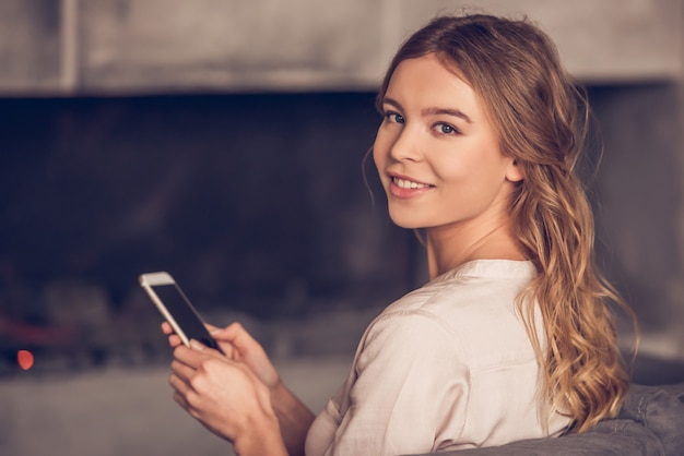 La donna in abbigliamento casual sta usando un telefono cellulare