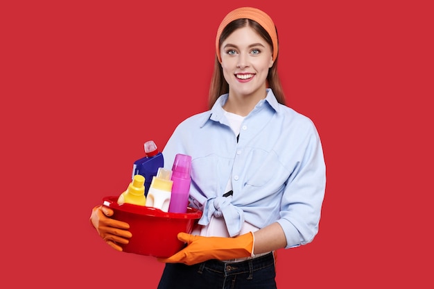 Woman in casual clothes and rubber gloves holding cleaning products