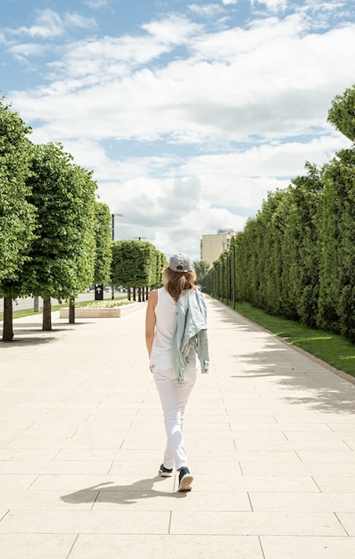 woman in casual jeans clothes walking outdoors holding her cap