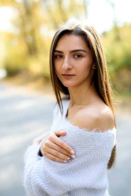 Woman in casual wear posing in park with yellow leaves