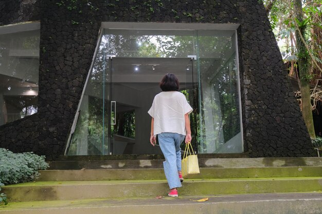 Photo woman casually walking up the steps into glass door entrance under the shade