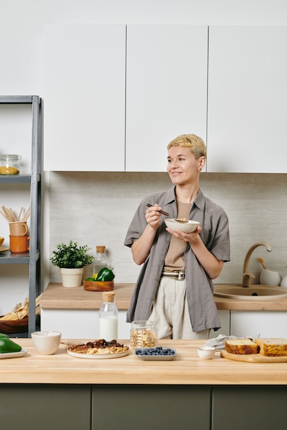 A woman in casualwear having breakfast in a kitchen