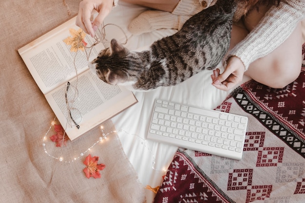 Woman and cat near book and keyboard