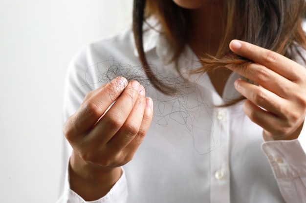 A woman catches a lot of hair falling from her scalp.