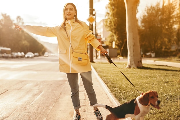 ひもにつないで犬と道路で車をキャッチする女性