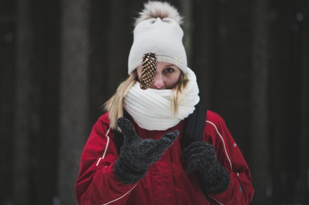 Photo woman catching pine cone during winter