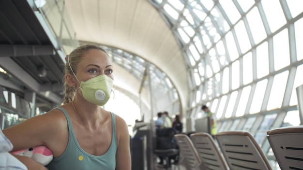 Фото Кавказская женщина в аэропорту с защитной медицинской маской на голове на фоне самолета coronavirus sarscov2 covid19