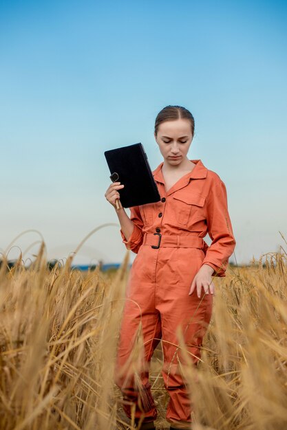 Кавказский технолог-агроном женщины с планшетным компьютером в области проверки качества и роста урожая пшеницы для сельского хозяйства. Концепция сельского хозяйства и сбора урожая.