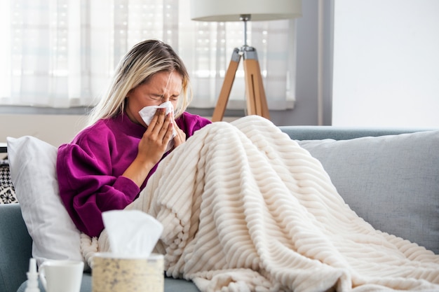 Woman Caught Cold and Flu Sneezing into Tissue.