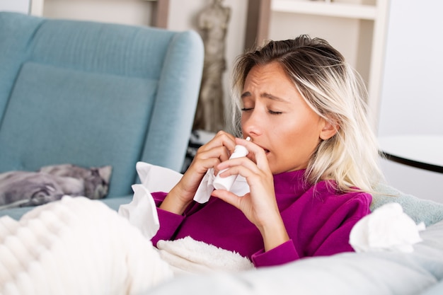 woman caught cold and flu sneezing into tissue.