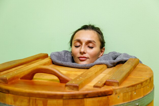 Woman in cedar spa barrel body rejuvenation and relax sauna