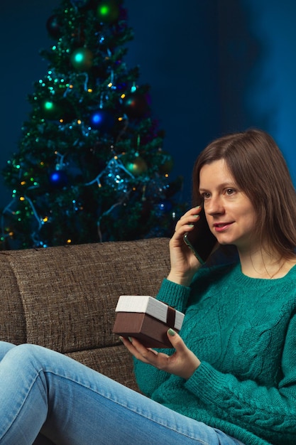 La donna festeggia la vigilia di natale con i parenti al telefono mostrando il regalo che riceve dai genitori