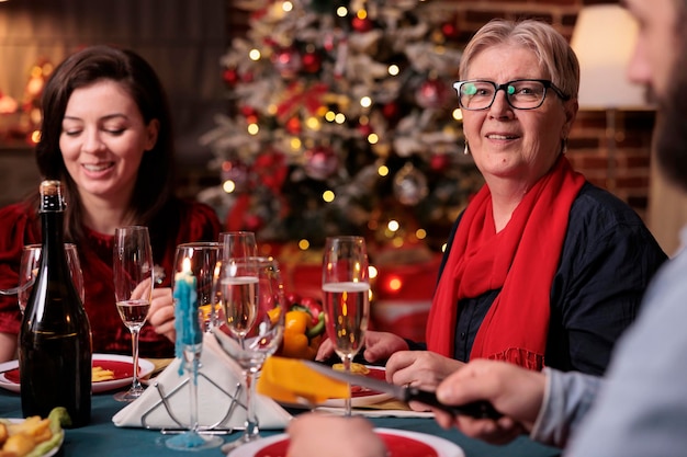 Woman celebrating christmas with family together, sitting at festive dinner table with mom at home party. Mother and daughter eating home cooked xmas food in decorated beautiful place