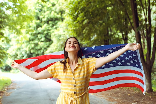 Женщина празднует день независимости и держит американский национальный флаг