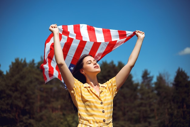 Женщина празднует день независимости и держит американский национальный флаг