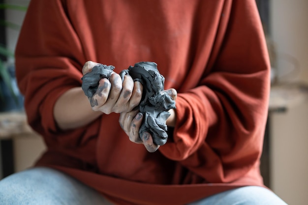 Woman ceramist wedging kneading clay while working at pottery studio