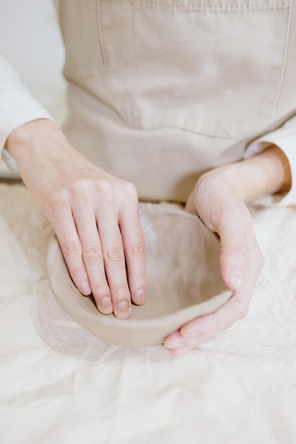 Woman ceramist in the workshop makes mugs out of clay small business or hobby is the creation of ceramic products