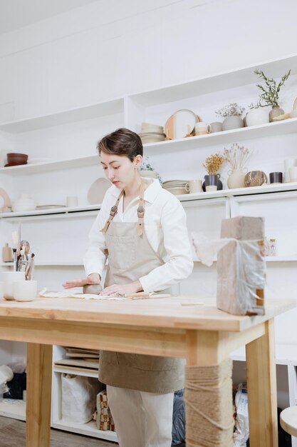 ワークショップの女性陶芸家は粘土の中小企業からマグカップを作りますまたは趣味はセラミック製品の作成です