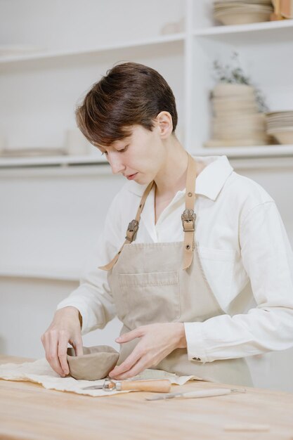 ワークショップの女性陶芸家は粘土の中小企業からマグカップを作りますまたは趣味はセラミック製品の作成です