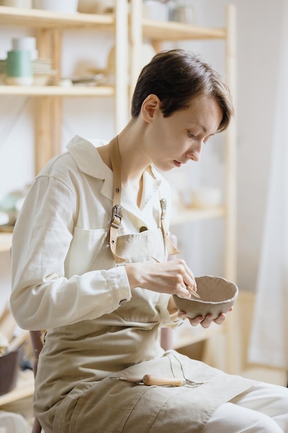 Woman ceramist in the workshop makes mugs out of clay small business or hobby is the creation of ceramic products