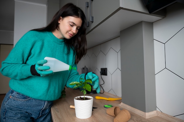 Photo woman changing pots of her plants at home during quarantine