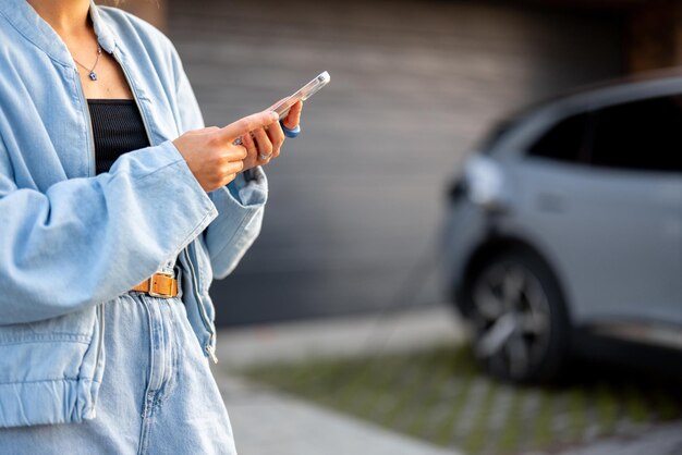 Woman charges her electric car near a house