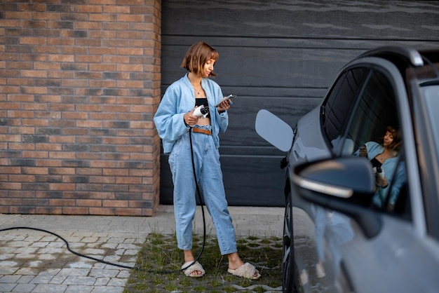 Woman charges her electric car near a house