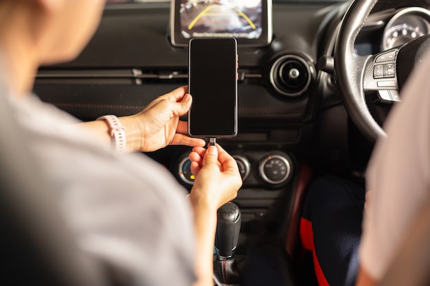 Photo woman charging battery smart phone in car