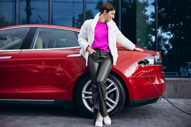 Photo woman charging electric car by the office building