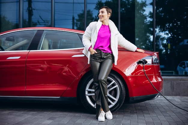 Woman charging electric car by the office building