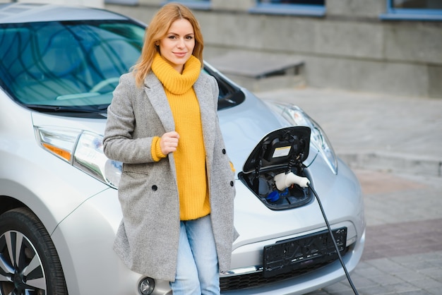 写真 電気ガソリンスタンドで電気自動車を充電する女性