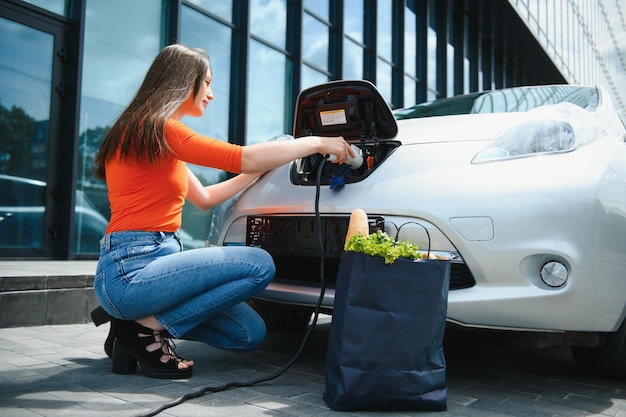 Donna che carica l'auto elettrica alla stazione di gas elettrica